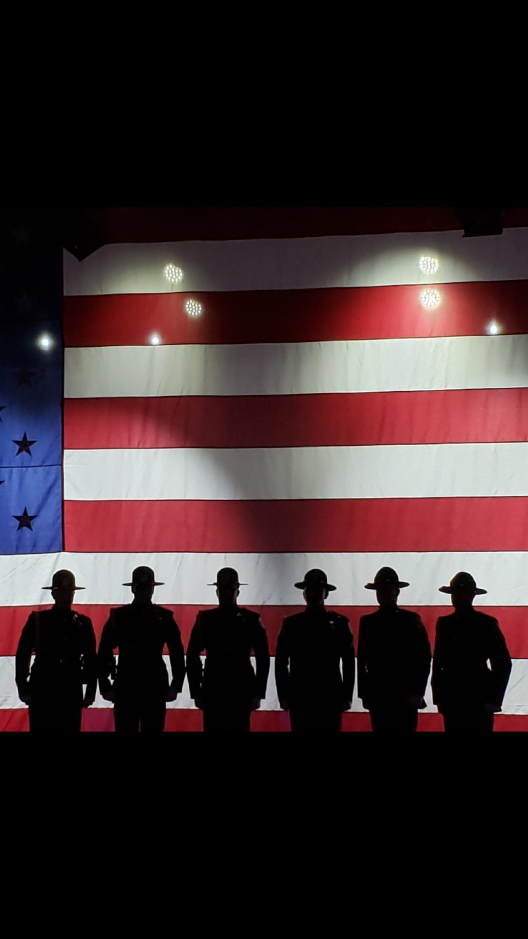 Silhouettes of riders in front of an American flag